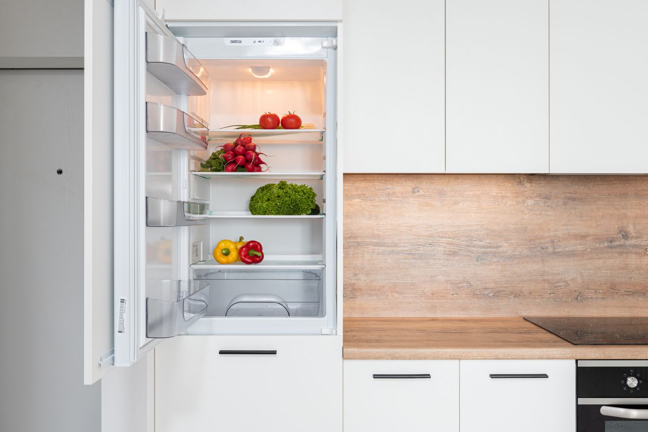 openstaande inbouwkoelkast in keuken met verschillende groenten